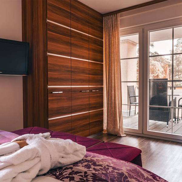 Blick vom Bett auf Schrankwand, Fernseher und Balkontür im Suite Apartment der Arkona Strandresidenzen Binz