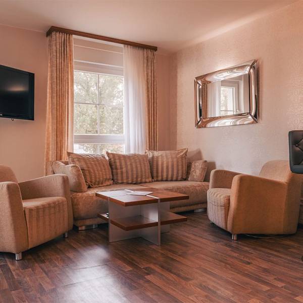 Wohnbereich im Suite Apartment der Arkona Strandresidenzen Binz mit Sofa, Sesseln, Couchtisch und Fernseher