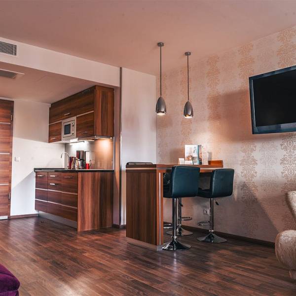 Küchenzeile mit Essbereich, Fernseher und Couch im Superior Studio der Arkona Strandresidenzen Binz