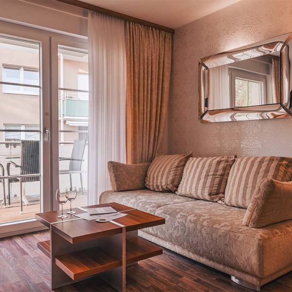 Wohnbereich im Apartment der Arkona Strandresidenzen Binz mit gemütlichem Sofa, Couchtisch und Balkonblick