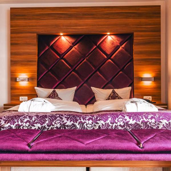 Blick auf das Doppelbett mit violettem Kopfteil und Tagesdecke im Studio in Binz