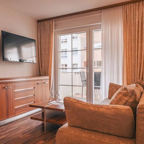 Wohnzimmer im Apartment der Arkona Strandresidenzen Binz mit Sofa, TV und Zugang zum Balkon