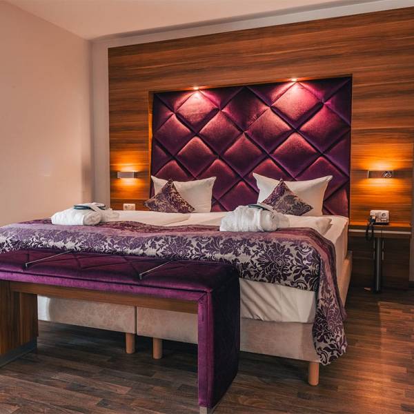 Doppelbett im Superior Studio des Arkona Strandresidenzen Binz mit gepolstertem Kopfteil und indirekter Beleuchtung