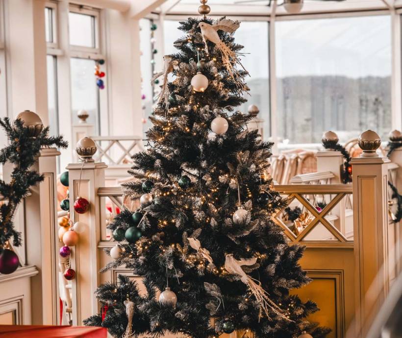 Ein festlich geschmückter Tannenbaum zu Weihnachten mit weißen und grünen Kugeln sowie weißen Tauben in den Arkona Strandresidenzen.