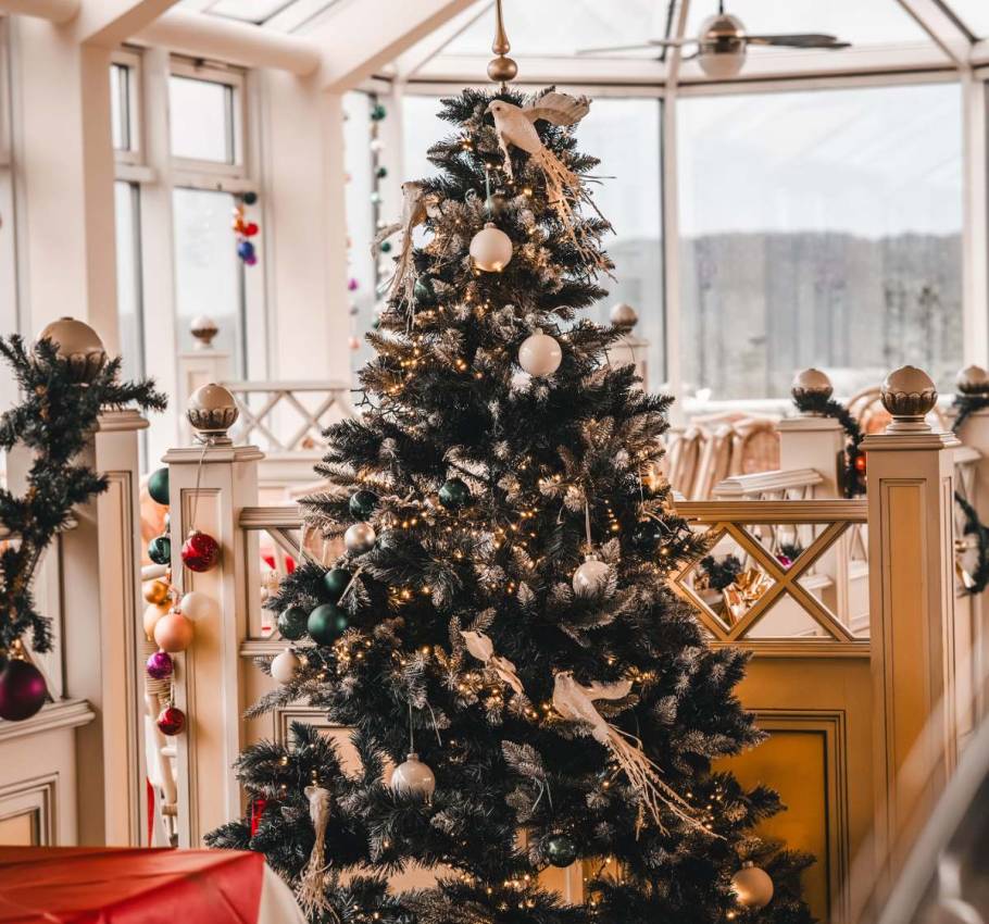 Ein festlich geschmückter Tannenbaum zu Weihnachten mit weißen und grünen Kugeln sowie weißen Tauben in den Arkona Strandresidenzen.