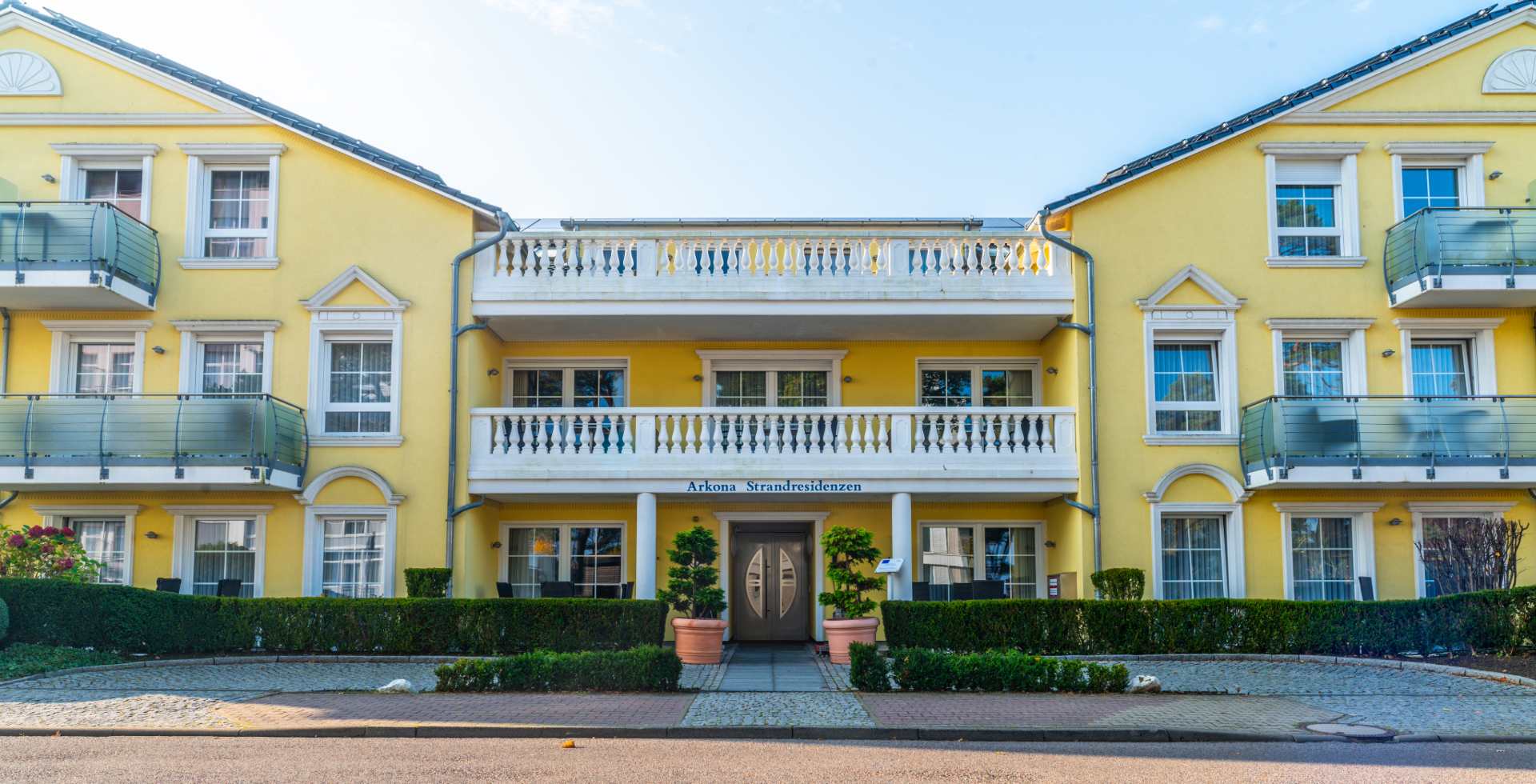 The yellow and white façade of the Arkona beach residences in sunny weather on the Binz beach promenade.